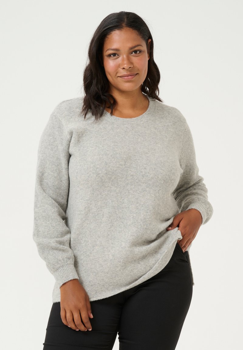 Light gray sweater made of soft, textured fabric. Features a round neckline and long sleeves, paired with black pants. Simple, neutral design.
