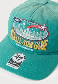 Πράσινο καπέλο μπέιζμπολ με κεντημένο το σιλουέτα της πόλης Σιάτλ από το All-Star Game MLB 2001, έναν πεφταστέρι και μια αυτοκόλλητη ετικέτα ’47 Hitch ρυθμιζόμενη στη γείσο.