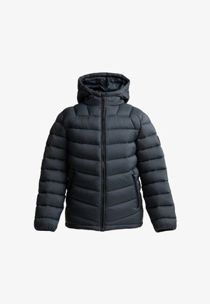 Tienerjongen staat, draagt een grijze donsjas met capuchon, een zwart Zavetti T-shirt en broek, en zwarte sneakers op een effen lichte achtergrond.