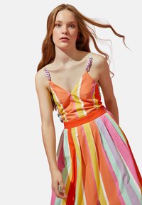 Farbenfrohes gestreiftes Kleid mit orange, pink, lavendel und grünen Farbtönen; hat Spaghettiträger und einen plissierten Rock.
