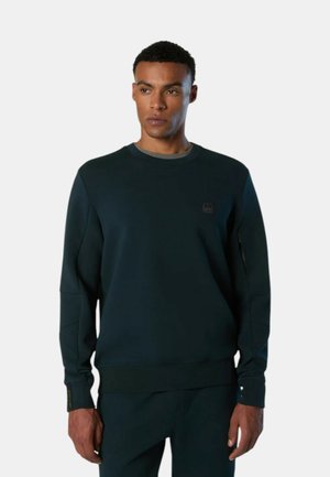 Felpa verde scuro in un tessuto morbido con scollo rotondo, polsini a coste e un piccolo dettaglio del logo sul petto. Texture liscia, vestibilità comoda.