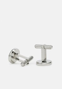 Boutons de manchette en métal argenté avec une base ronde et un design en T-bar, texture lisse et finition polie. Style minimaliste et moderne.