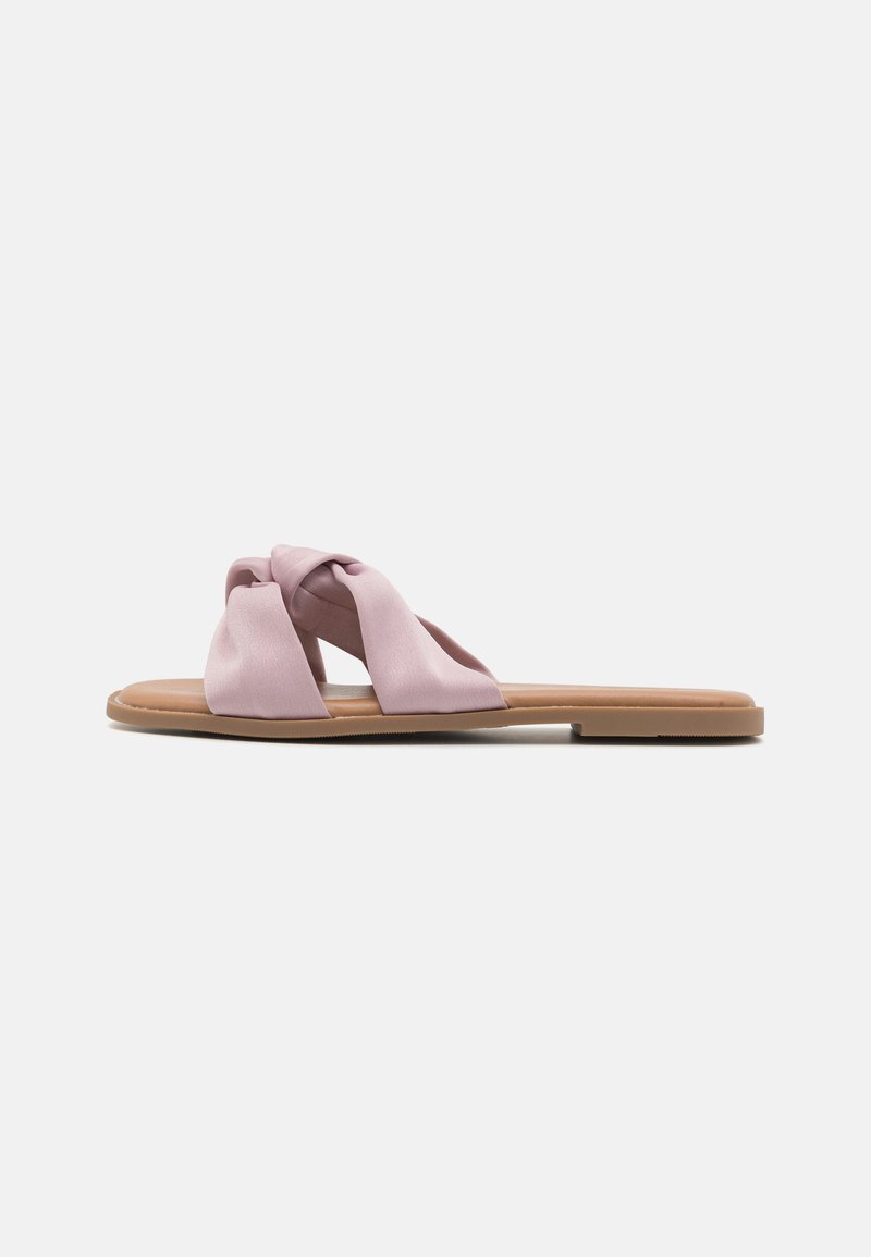 Flate sandaler med en knyttet overdel i lys rosa sateng, med en brun gummisåle og minimalistisk design. Glatt tekstur hele veien.