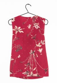 Haut sans manches rouge avec motif floral en crème et rose, doté d'un col rond et d'un ourlet droit, suspendu à un cintre noir.