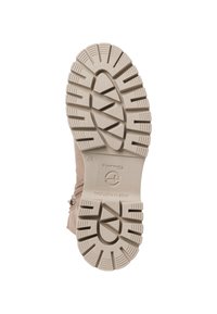 Beige laarzensol met een gestructureerd rubberontwerp, voorzien van duidelijke profielvlakken, groeven en een logo, wat duidt op duurzaamheid en grip.