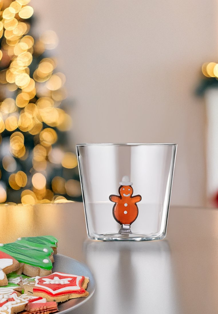 Glasklarer Becher mit einem braunen Lebkuchenmann-Design und einem weißen Hut. Glatte Oberfläche, zylindrische Form, steht auf einer flachen Unterlage.