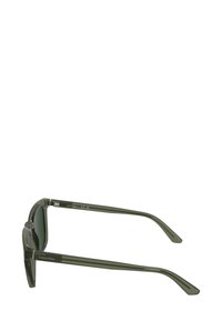 Occhiali da sole in plastica verde con montatura rettangolare, caratterizzati da una parte frontale trasparente e aste solide, con il marchio "Calvin Klein" sul lato.