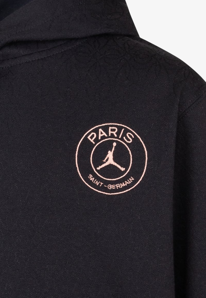 Hoodie noir en tissu texturé, avec un logo rose brodé en rond portant l'inscription "PARIS SAINT-GERMAIN" et une silhouette de Jordan.