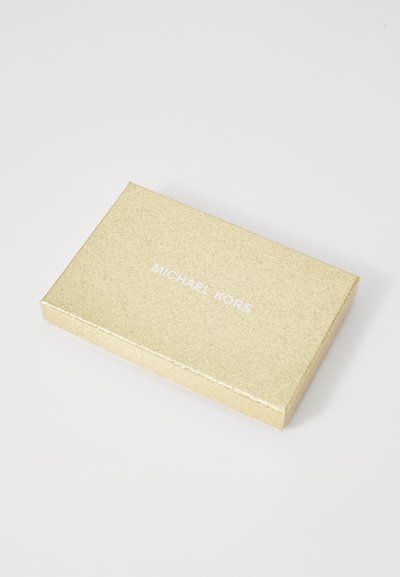 Boîte cadeau en or scintillant avec une texture lisse. Présente "MICHAEL KORS" imprimé en blanc. Forme rectangulaire avec des bords nets.