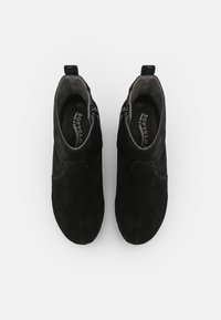 Un par de botas de tobillo de ante negro con cremalleras laterales y plantillas de la marca Softclox, vistas desde arriba sobre un fondo blanco.