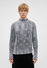 Γκρι πλεκτό πουλόβερ με αστεράκια, διαθέτ�ει ψηλό γιακά και φερμουάρ στο πλάι, κατασκευασμένο από υφασμάτινη υφή, εφαρμοστή γραμμή με μακριά μανίκια.