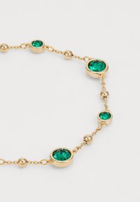 Gouden armband met groene facetstenen en ronde metalen kralen op een delicate ketting, die een mix van gladde en gestructureerde elementen laat zien.