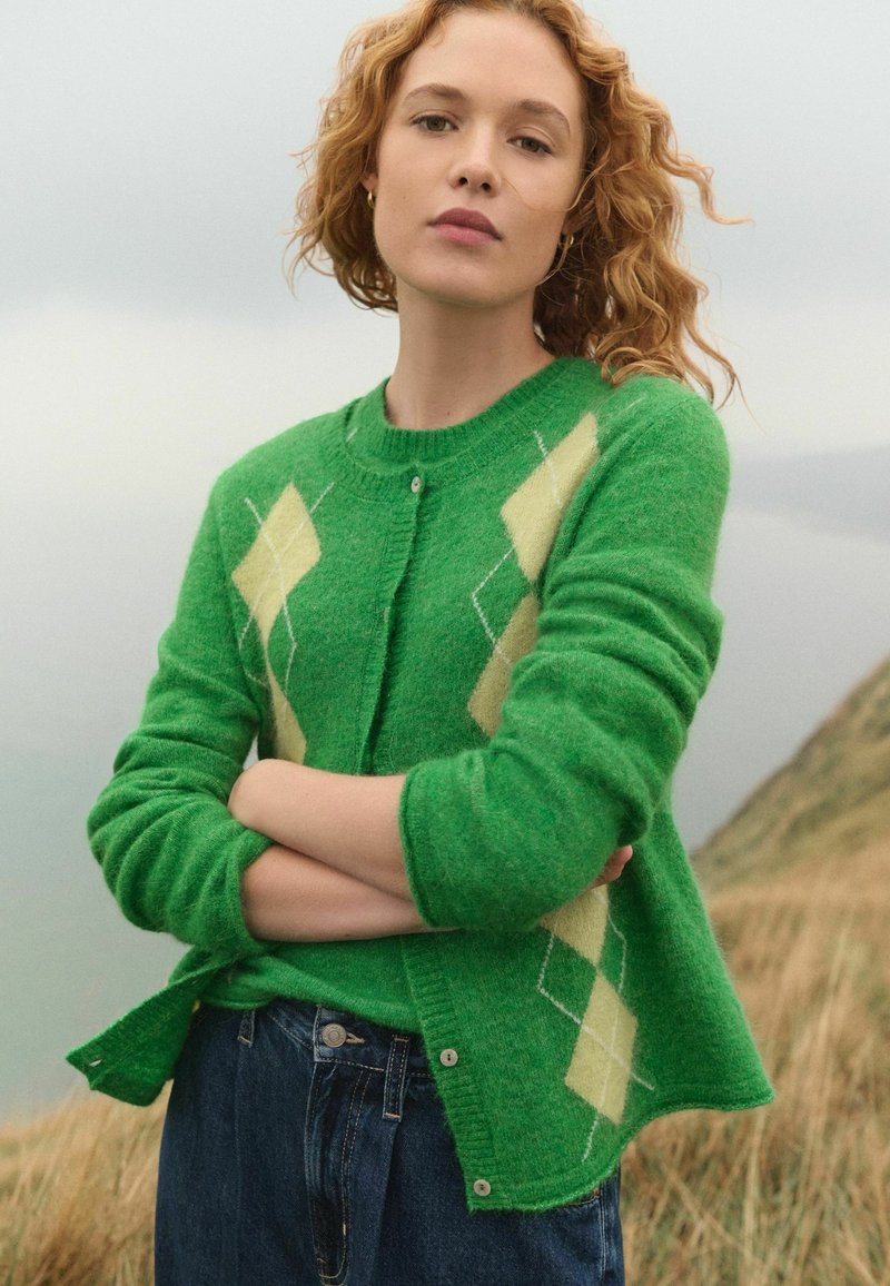 Groene wol cardigan met een gestructureerde afwerking, met een ruitpatroon in lichtgeel en wit. Rond de hals en met knoopsluiting.