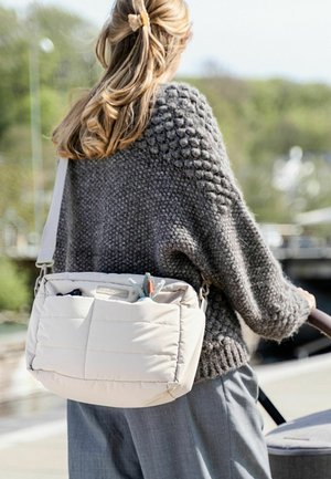 Bežna prešita torba preko ramena z teksturirano sprednjo stranjo, ki vsebuje žepe z majhnimi plišastimi igračkami. Sivi pleteni pulover z ohlapnim krojem.