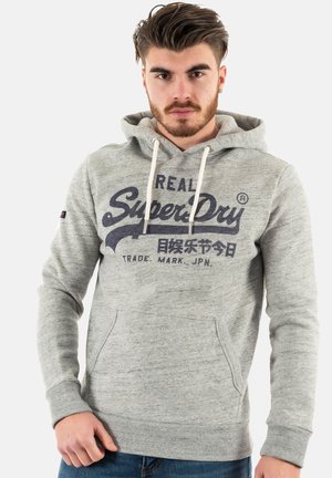 Felpa grigia con tasca a marsupio, cordini regolabili e logo "SuperDry" in blu scuro. Realizzata in un morbido tessuto testurizzato.