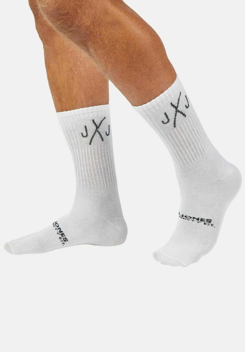 Weiße Sportsocken mit geripptem Muster, kontrastierenden schwarzen Logoakzenten und JXJ-Branding am Bündchen und an der Sohle.