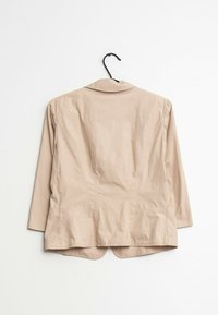 Béžové lehké sako s jedním límcem, dlouhými rukávy a zaobleným lemem. Vyrobeno z hladké látky, která má jemnou texturu.