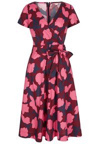 Robe portefeuille en tissu bordeaux, ornée de motifs floraux roses. Manches courtes, décolleté en V et détail de taille nouée soulignent sa silhouette.