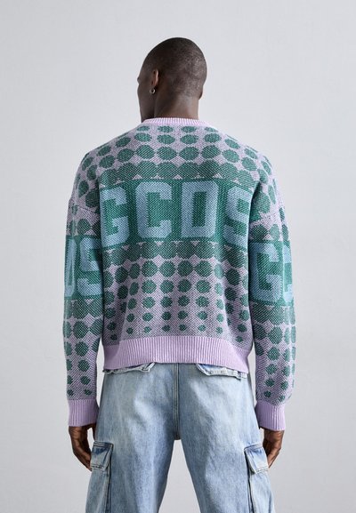 Pulover tricotat în verde și lavandă, cu un model geometric și text mare "GCDS." Mânecile și tivul cu margini ondulate, croială lejeră.