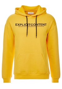 Żółta bluza z kapturem uszyta z miękkiego materiału, z kieszenią kangurką, czarnymi sznurkami i wyraźnym napisem "TREŚCI EKSPLICYTNE" z przodu.