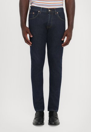 Jean en denim bleu foncé à coupe slim, avec un design classique à cinq poches et des accents en métal de couleur cuivre.