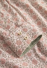 Camicia a fantasia floreale con toni di rosa e verde, in cotone, leggera, con bottoni bianchi e un accento verde sui polsini.