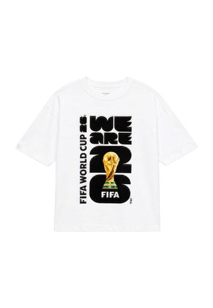Hvid T-shirt med sort tekst "WE ARE 2026" og "FIFA WORLD CUP 26" sammen med et stort billede af FIFA World Cup-trofæet i guld.