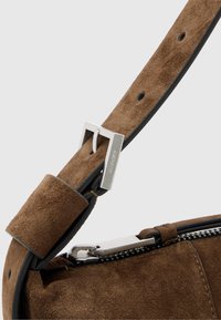 Brązowy pasek do torebki zamszowej z srebrną metalową klamrą i dodatkami. Pasek ma miękką teksturę i czysty design z detalem zamka błyskawicznego.