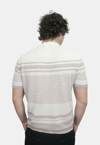Maglione grigio chiaro a maniche corte in maglia, con strisce orizzontali di larghezze variabili. Presenta un colletto a girocollo e polsini a coste.