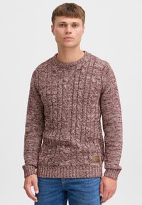 Pull en maille bordeaux avec motif en câble, manches et ourlet côtelés, fabriqué à partir de fil texturé. Étiquette en cuir à l'ourlet indiquant la marque.
