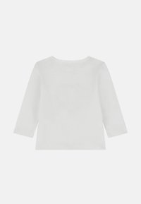 Camicia bianca a maniche lunghe realizzata in tessuto morbido, caratterizzata da un collo rotondo e un taglio dritto. Design minimalista senza motivi o accenti.