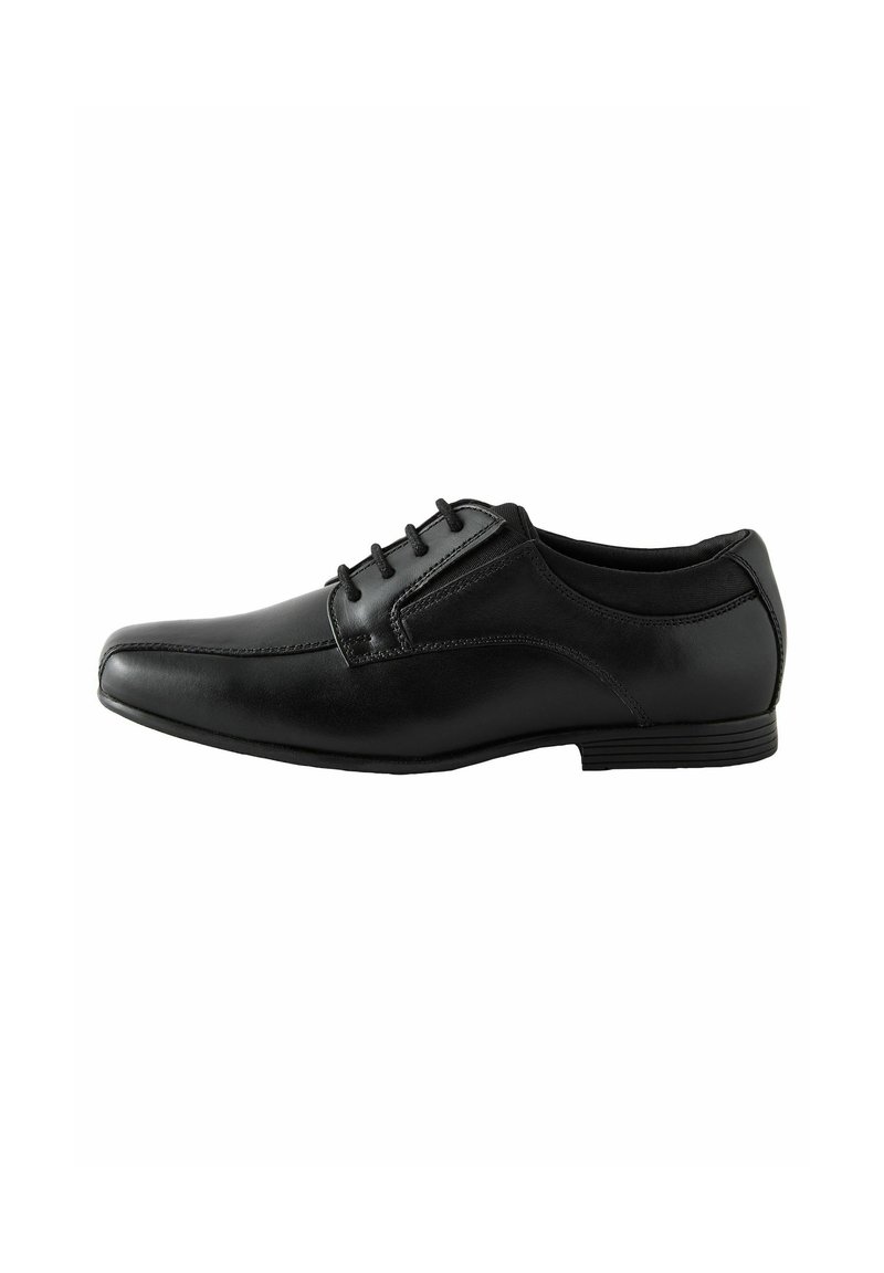 Zapato de vestir de cuero negro con un diseño elegante, que presenta cinco ojales y un tacón bajo. La vista lateral muestra un acabado suave y una silueta moderna.
