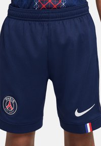 Pantaloni sportivi navy con vita elastica, caratterizzati dal logo del Paris Saint-Germain e dallo swoosh bianco di Nike. Include dettagli a strisce rosse, bianche e blu.