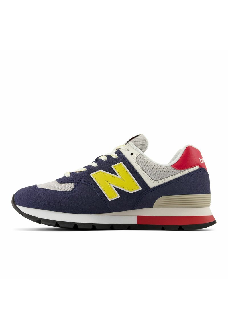Chaussure de sport bleu marine et grise avec un logo "N" jaune, un accent rouge au talon, une semelle blanche, en daim et maille, avec des coutures contrastées.