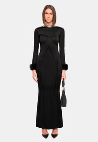 Schwarzes Langarmkleid mit figurbetontem Schnitt, mit Pelzbesatz an den Ärmeln, glatter Textur und strukturierten Details am Oberteil.