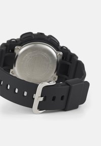 Orologio in gomma nera con fibbia in metallo, dotato di un retro circolare in acciaio inossidabile e quella trama sui lati.