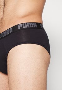 Schwarze Herrenunterhosen mit einem strukturierten schwarzen Bund, der das "PUMA"-Logo trägt, aus weichem Stoff mit enger Passform.