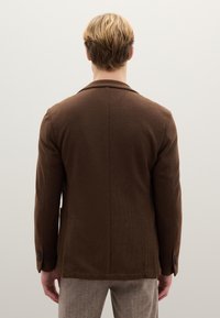 Brauner, maßgeschneiderter Blazer mit glatter Textur, Reverskragen und zwei Rückenschlitzen. Verfügt über Knopfdetails an den Manschetten.