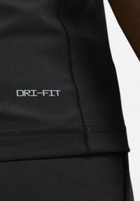 Must musta Dri-Fit sportlik särk, millel on sile tekstuur, lame õmblused ja valgete tähtedega "DRI-FIT" logo asub külje peal.