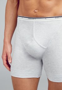Boxer da uomo in cotone grigio con vita elasticizzata, caratterizzati da dettagli in bianco e nero. Design attillato con una tasca frontale di supporto.