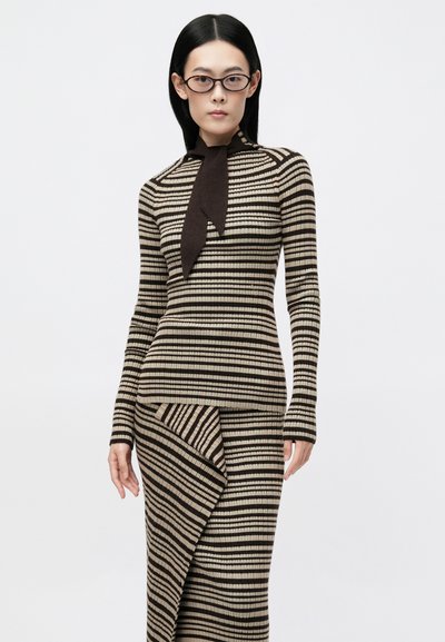 Top e saia de malha listrados em bege e castanho. O top tem uma gola alta com um laço. A saia apresenta uma bainha assimétrica e um tecido texturizado.