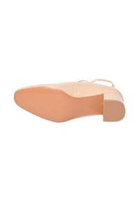 Tacco nudo in pelle verniciata con punta tonda, un tacco basso a blocco e una suola in gomma testurizzata. Dettaglio della fascia sulla parte superiore del piede.