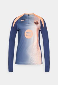 Haut d'entraînement en bleu et pêche à manches longues de Nike, avec le blason du FC Barcelone et le logo de Spotify, un col zippé et un motif de lignes abstraites.