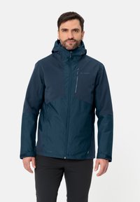 Navyblauwe waterdichte jas met capuchon, voorzien van een rits aan de voorkant en contrasterend paneelontwerp. Zachte textuur en functionele zakken zijn inbegrepen.