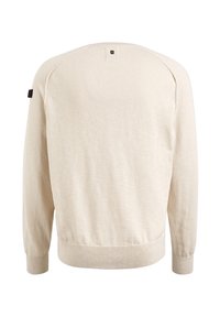 Beige trui met een zachte textuur, geribbelde manchetten en zoom, en een klein zwart label op de linkerschouder. Heeft een ronde hals en raglanmouwen.