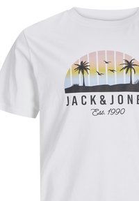 White cotton t-shirt featuring a graphic with palm trees, a gradient sunset with birds, and text reading "JACK&JONES Est. 1990" in black.