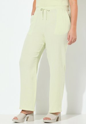 Lichtgroene, gestructureerde broek met een elastische tailleband, een koord en twee voorzakken. Gecombineerd met beige open teen schoenen met blokhak.
