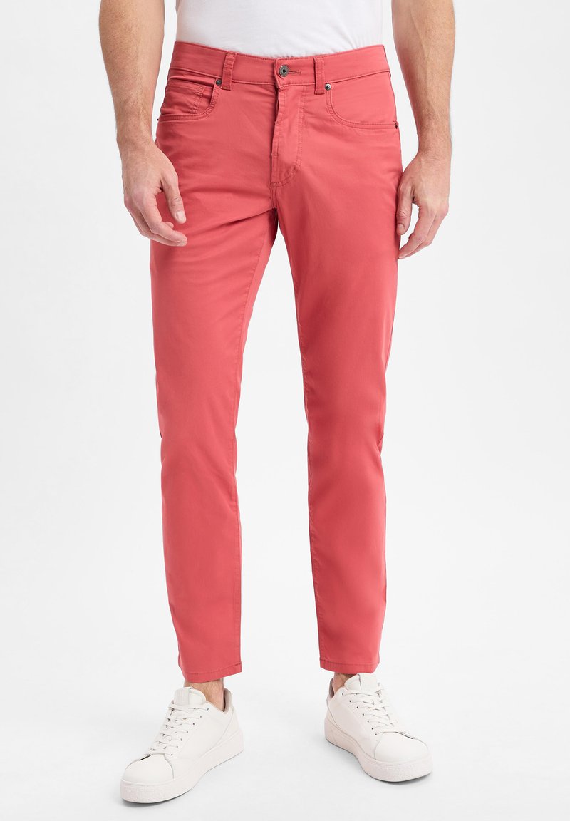 Rote Baumwollhose mit slim fit, ausgestattet mit vorderen Taschen und einem Knopfverschluss, kombiniert mit weißen Sneakern. Glatte Textur über die gesamte Fläche.