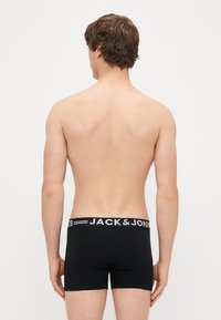 Mustat puuvillaboksereiden alusvaatteet, joissa on kontrastivalkoinen vyötärönauha, jossa lukee "JACK & JONES". Silkkinen pinta, mukautuva muotoilu.