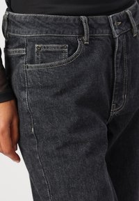 Dark denim jeans with a slim fit, featuring contrast stitching, metal hardware accents, and a classic five-pocket design.